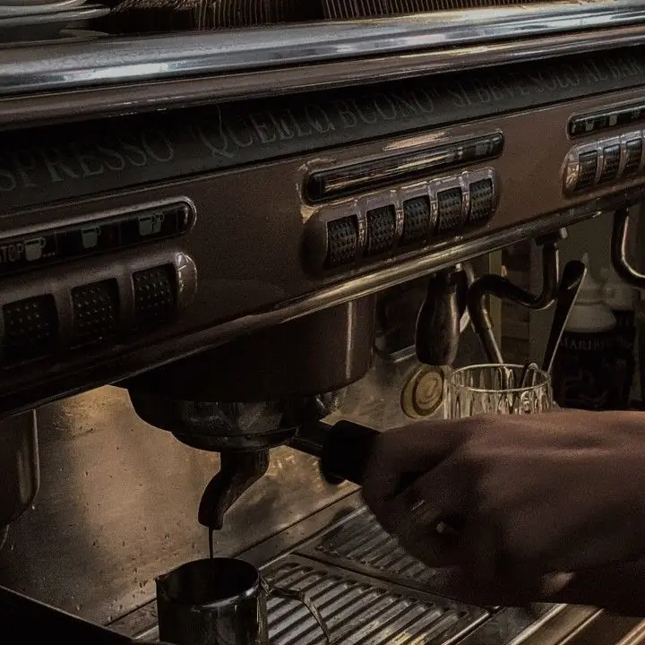 A shot of espresso running into a steel jug