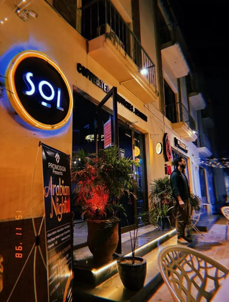Café Sol at night, its round SOL sign lit over the entrance