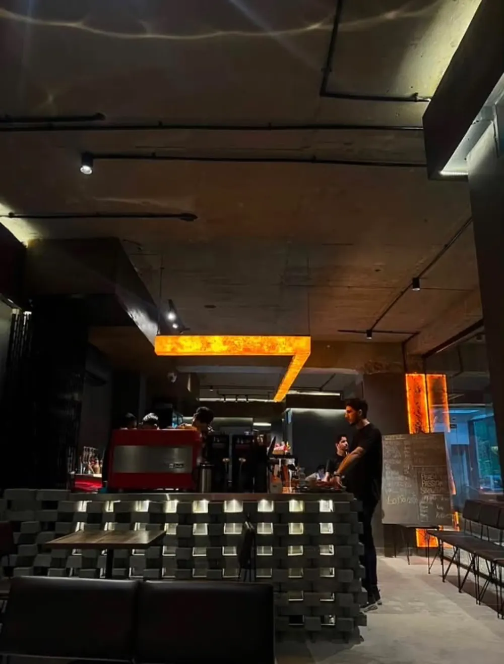 The bar at Ninety Plus under an amber onyx light, a red espresso machine at work